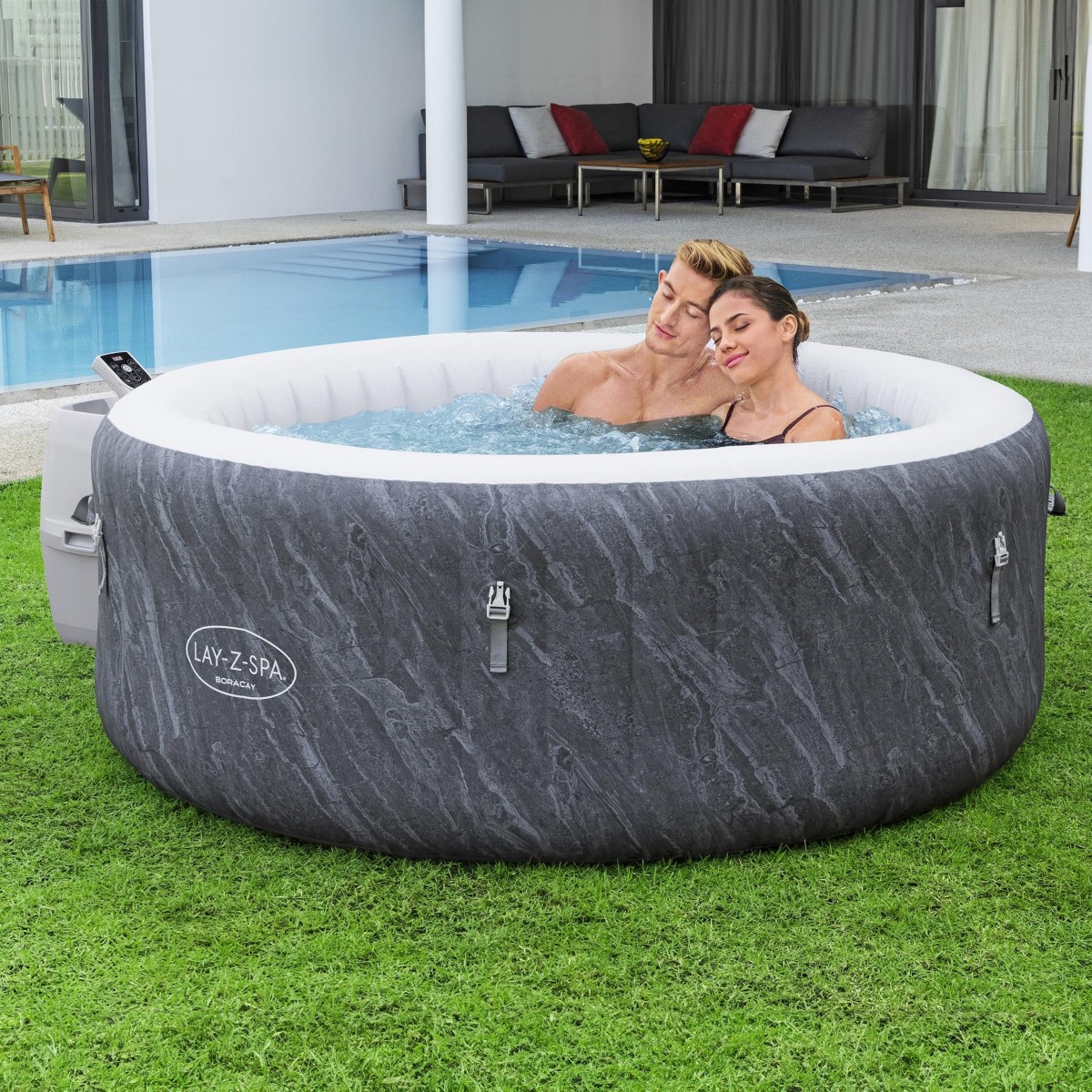 Zestaw jauzzi Lay-Z-Spa Boracay w użyciu: dwie osoby relaksują się w okrągłym dmuchanym jacuzzi ogrodowym z włączonym hydromasażem.